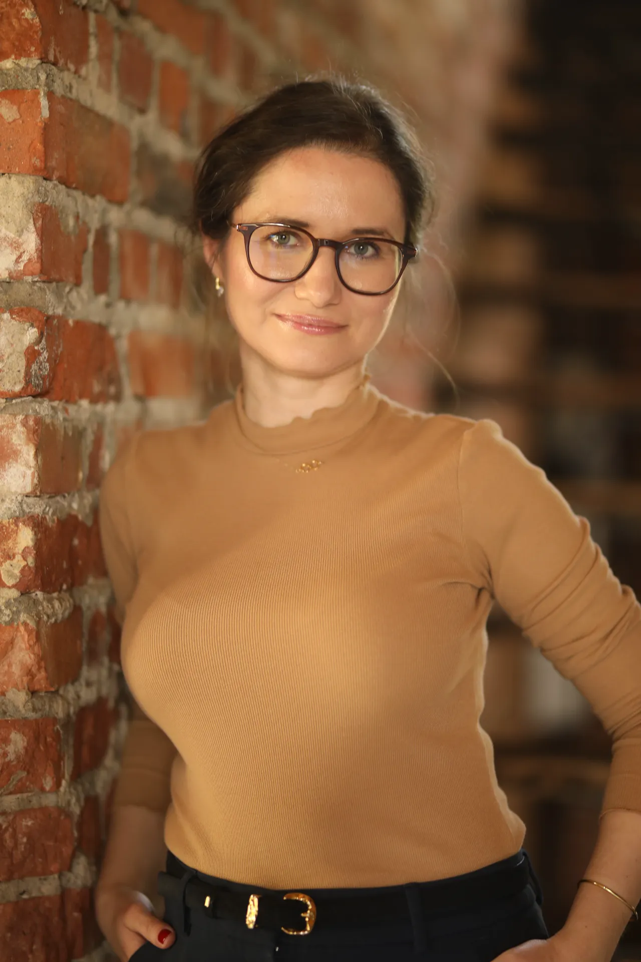 Magdalena Żurawska w gabinecie na tle ceglanej ściany